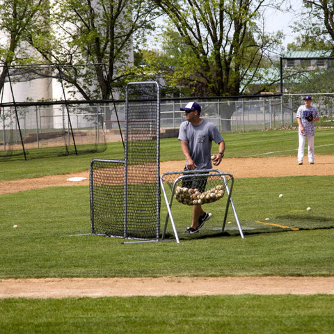 Man using 6Ft Black L Screen For Baseball And Softball Batting Practice With UV Treated Net And Steel Frame Durable Portable Pitching Screen For Backyard And Field Training Easy To Move And Set Up on field