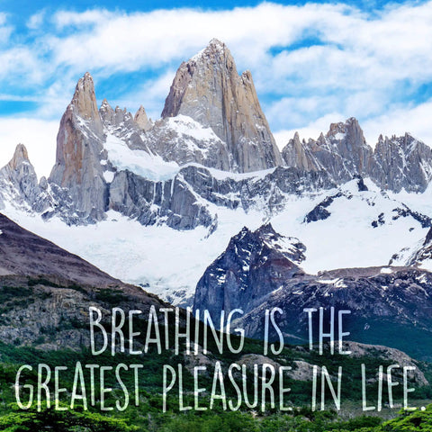 Mountain landscape with the phrase 'Breathing is the greatest pleasure in life' overlaid on snow-capped peaks and blue sky.