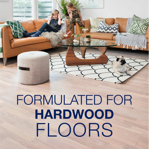 Living room with hardwood floors, two children on a brown couch, and a pug in foreground, showcasing Low Gloss Hardwood Floor Polish That Revives Dull Wood And Gives A Smooth, Home Ready Shine, Protects And Renews Polyurethane Finishes, Safe For Unwaxed Or Unoiled Floors, Not A Cleaner, Covers Up To 500 Sq Ft in use.
