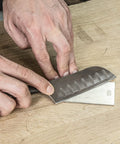 Person using All In One Credit Card Diamond Sharpening Kit With 180 300 Grit And 600 1000 Grit Stones to sharpen a knife on wood