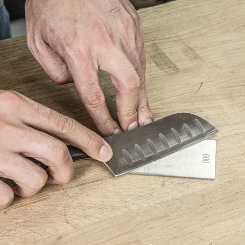 Person using All In One Credit Card Diamond Sharpening Kit With 180 300 Grit And 600 1000 Grit Stones to sharpen a knife on wood