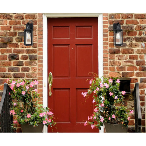 Super Practical Traditional One Light Outdoor Wall Fixture With Motion Sensor Dusk To Dawn Sensor Matte Black Clear Glass Lantern next to a red entry door