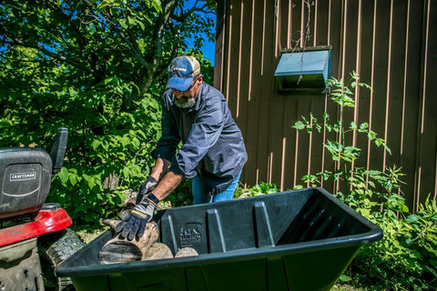 Man loading rocks into Heavy Duty Lawn And Garden Trailer With 900 Lb Capacity 15 Cu Ft Poly Tub Tilt And Pivot Frame Sealed Bearings