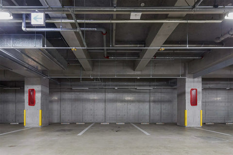 Rugged Outdoor Fire Extinguisher Cabinet Lock Box Red Weatherproof Steel Holder mounted in a parking garage for safety.