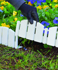 Hands installing No-Dig Landscape Edging Kit with anchoring spikes as 4.5 inch tall white wood-look garden border around flowers.