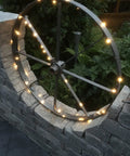 Solar String Lights 16 Feet 50 LEDs Warm White Two Pack Outdoor Fairy Lights on wagon wheel, garden display at dusk.