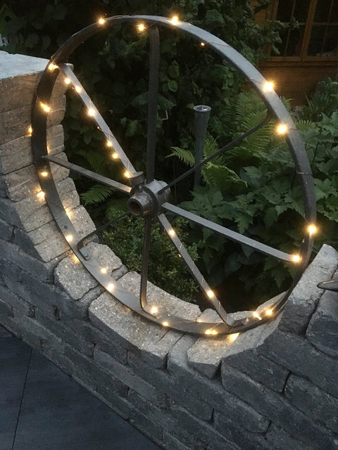 Solar String Lights 16 Feet 50 LEDs Warm White Two Pack Outdoor Fairy Lights on wagon wheel, garden display at dusk.
