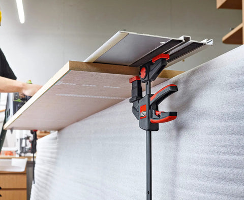 EZR Set Dope One Hand Table And Track Clamp holding a wooden panel with quick release and soft touch pads in a woodworking setup.