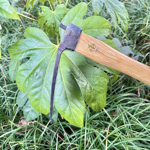 14 Inch Heavy Duty Curved Garden Hoe With Oak Handle for digging and weeding, shown against green foliage.