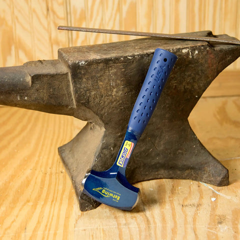 Heavy Duty 4 Pound Drilling And Crack Hammer, USA Made Sledge Hammer with blue grip against an anvil on wooden floor