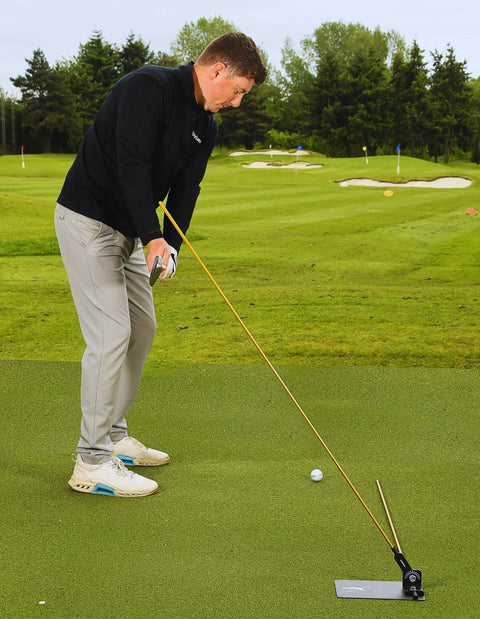 Golfer using Pro Grade Golf Swing Trainer Plate with 2 Premium Gold Alignment Rods on green, swing analyzer aid in action.