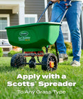 Person using a green Scotts Turf Builder spreader on a lawn