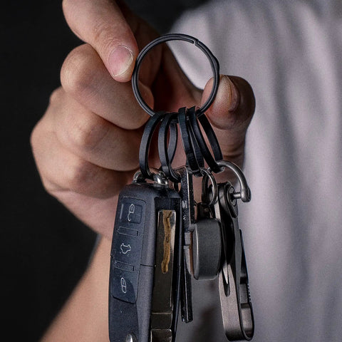 Person holding Heavy Duty Titanium Key Ring Set With Side Push Design For Easy One Hand Access Split Keyring And Carabiner Keychains