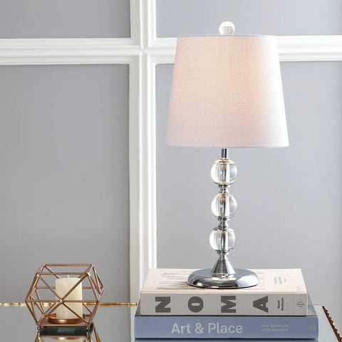 Clear Crystal 20 Inch Mini LED Table Lamp In Chrome Finish With White Linen Drum Shade on a stack of books in a living room setting