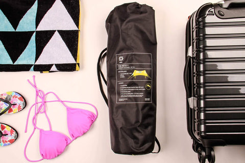 Lightweight 7x7 Foot Beach Tent Sun Shelter With Sand Anchors bag next to suitcase and beach items