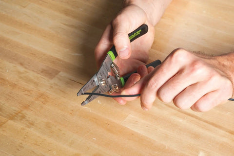 Person using stainless steel wire stripper for 10-18 AWG solid and 12-20 AWG stranded on a wooden table