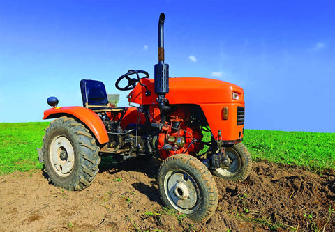 An orange tractor on a green field with blue sky background.