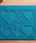 12 By 10 Inch Heart Inlay Router Template Guide Kit For Woodworkers Straight Up Perfect Decorative Doughnut Jigs Making Eight Sizes No Sweat Routing Every Time displayed on a cutting mat.