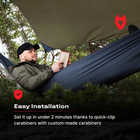 Man relaxing in a hammock under 12x10 Rain Fly Tarp For Survival Camping, Ultra Lightweight Waterproof Shelter with durable 210T polyester.