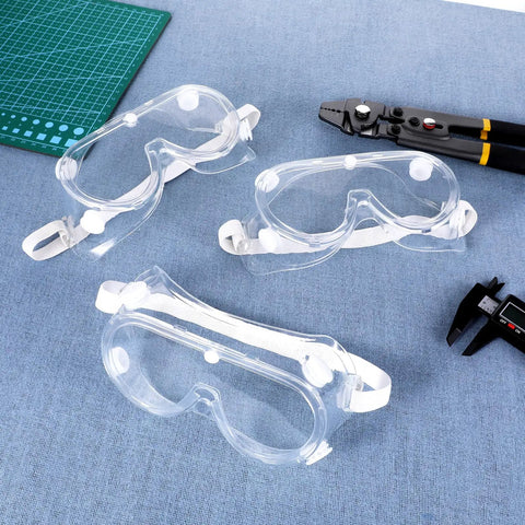 Three clear Ten Pack Anti Fog Lab Goggles Over Glasses Safety Eyewear with Soft Silicone Lenses on blue surface with tools.
