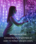 Person decorating tree with 65.6 Feet Indoor Outdoor Smart RGB LED String Lights With Over 16 Million Dope Colors, creating vibrant ambiance.