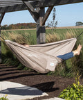 Person relaxing in Double Polyester Mesh Hammock Packable For On The Go Chill Holds Up To 400 Lbs portable and compact in garden.