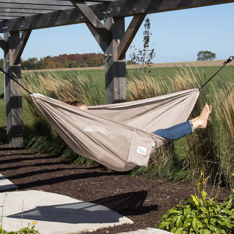 Person relaxing in Double Polyester Mesh Hammock Packable For On The Go Chill Holds Up To 400 Lbs portable and compact in garden.
