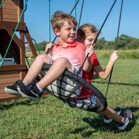 Children playing on web swing of Cedar Cove Wooden Swing Set With Spiral Tube Slide And Wave Slide for backyard playtime
