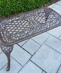 Antique bronze Mississippi Cast Aluminum Outdoor Cocktail Table 35 Inch Long By 18 Inch Wide with ornate design on patio.