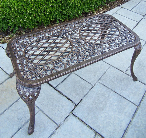 Antique bronze Mississippi Cast Aluminum Outdoor Cocktail Table 35 Inch Long By 18 Inch Wide with ornate design on patio.