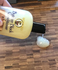 Deep Penetrating Food Grade Butcher Block Conditioner poured on wooden surface with hand holding bottle