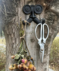 Badass Vintage Cast Iron Beard Shaped Wall Hook Kit With Heavy Duty Screws For Hanging Coats Scarves Bags And Keys While Adding Hecka Cool Antique Decor Flair To Any Entryway Or Bedroom Space with scissors and dried flowers on a tree.