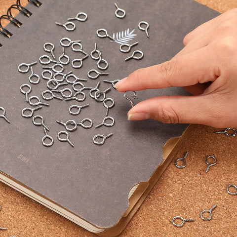 Person holding Heavy Duty Screw Eye Hooks 0.63 Inch from 300 Pack Durable Iron Eye Screws for Hanging Artwork, Pictures, and Outdoor Use