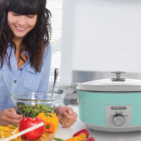 Woman preparing salad beside Teal 7 Quart Slow Cooker With Built In Lid Holder, Cool Touch Handles, 3 Heat Settings