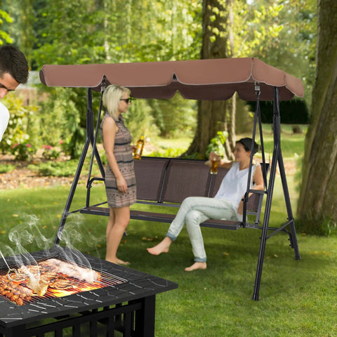 Three Seat Outdoor Porch Swing With Adjustable Canopy, Armrests And Included Stand in a backyard setting with people relaxing.