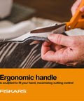 Close-up of orange handle stainless steel scissors cutting fabric, ergonomic design for all purpose cutting tasks.