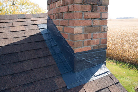 Chimney Flashing Sealer And Roof Sealant That Keeps Water Out applied on brick chimney flashing with roof shingles, 2.2 kg product in use.