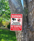 Heavy Duty No Dumping And Video Surveillance Warning Signs 2 Pack 14 X 10 Inch Reflective Aluminum Plate mounted on tree for property protection.