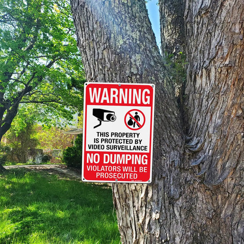 Heavy Duty No Dumping And Video Surveillance Warning Signs 2 Pack 14 X 10 Inch Reflective Aluminum Plate mounted on tree for property protection.