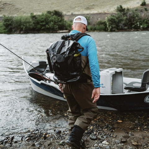 Angler on shore with Rum Runner Gage Tech Waterproof Backpack For Fishing And Outdoors Fully Waterproof Angler Gear Carrier