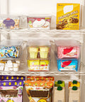 Top Shelf Eight Piece Clear Stackable Storage Bins With Slick Snap Lids, organized pantry shelf display of snacks.