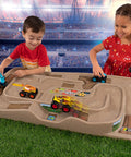 Children playing with the On The Go Kid Friendly Race Track Table With 2-Sided Play Surface For Cars And Trains in a stadium-like setting
