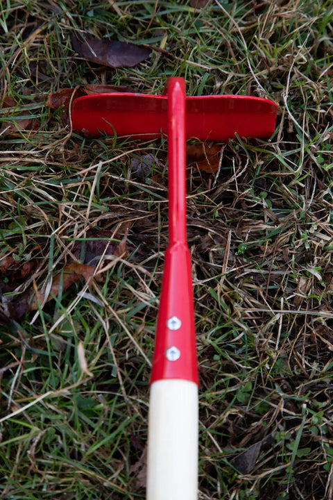 Kids Garden Tool Set 4 Piece Rake Spade Hoe And Leaf Rake With Real Wood Handles And Steel Heads, red hoe on grass.