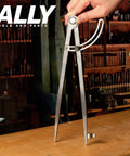 12 Inch Heavy Duty Woodworking Compass With Quick Draw Wing Divider And Clip On Pencil Rest positioned on a wood surface.