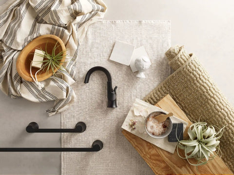 Flat lay with Doux Matte Black 24-Inch Single Towel Bar for Bath and Kitchen, faucet, and decor items on linen and wood surface.