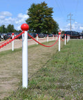 Outdoor installation of red plastic barrier chain on white posts
