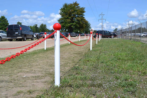 Outdoor installation of red plastic barrier chain on white posts