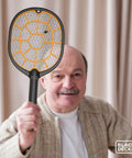 Older man holding Cordless Electric Fly Swatter Racket For Gnats And Mosquitoes Outdoor Indoor Bug Zapper Handheld Battery Powered Pest Control Tool For Home Patio Garden Safe For Humans Fast Easy Bug Busting.