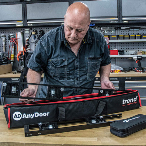 Man examining components of All-In-One Adjustable Door Hinge Jig Installation Kit For 2 Ft 6 In To 9 Ft Doors in a workshop