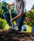 Person using 202 Pro Ergonomic Stainless Steel Shovel With Round Point Blade For Clay And Rocky Soil in garden setting.